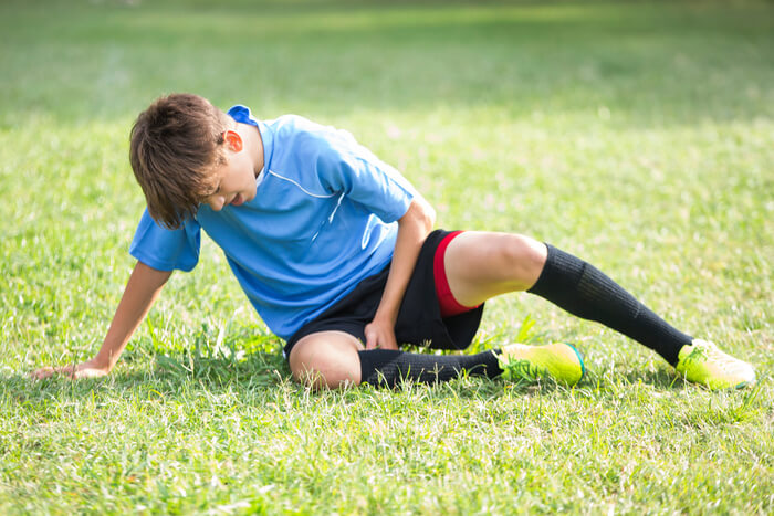 Young student athlete injured or tired on field.