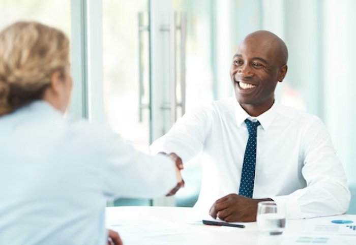 Man and woman shaking hands from across a table