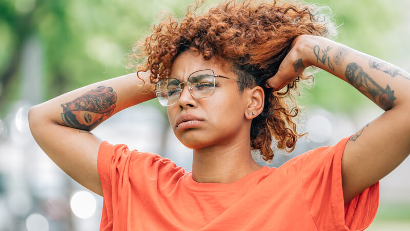 Young woman outside holding hair up to cool off.