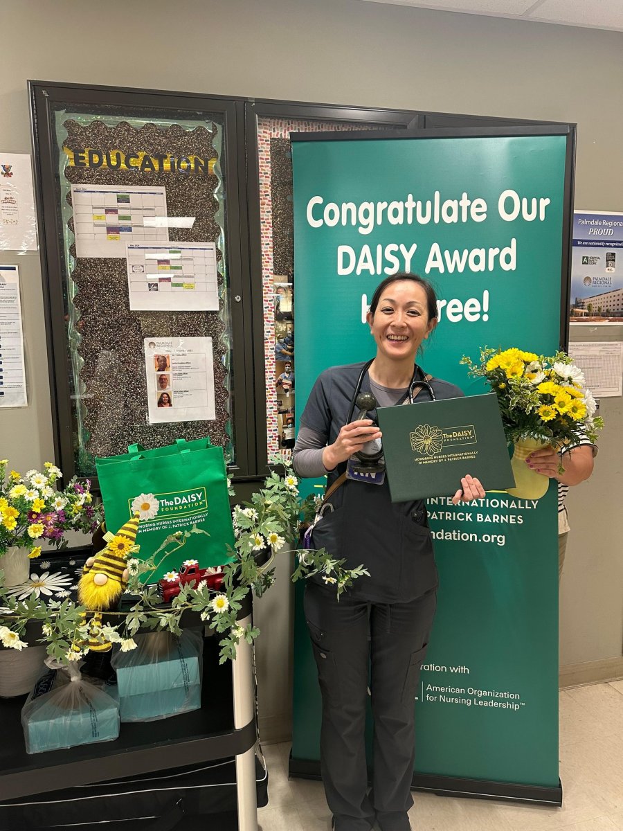 Hiroe Okamoto holding her DAISY award and a bouquet of daisies.