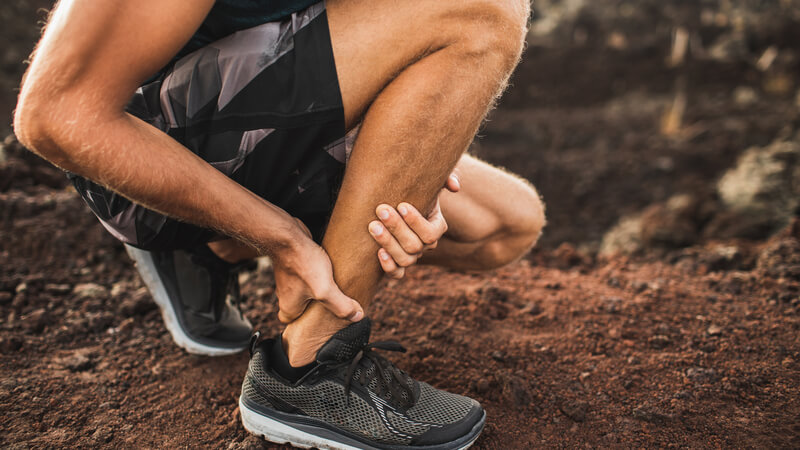 Athlete rubbing injured ankle mid-run.